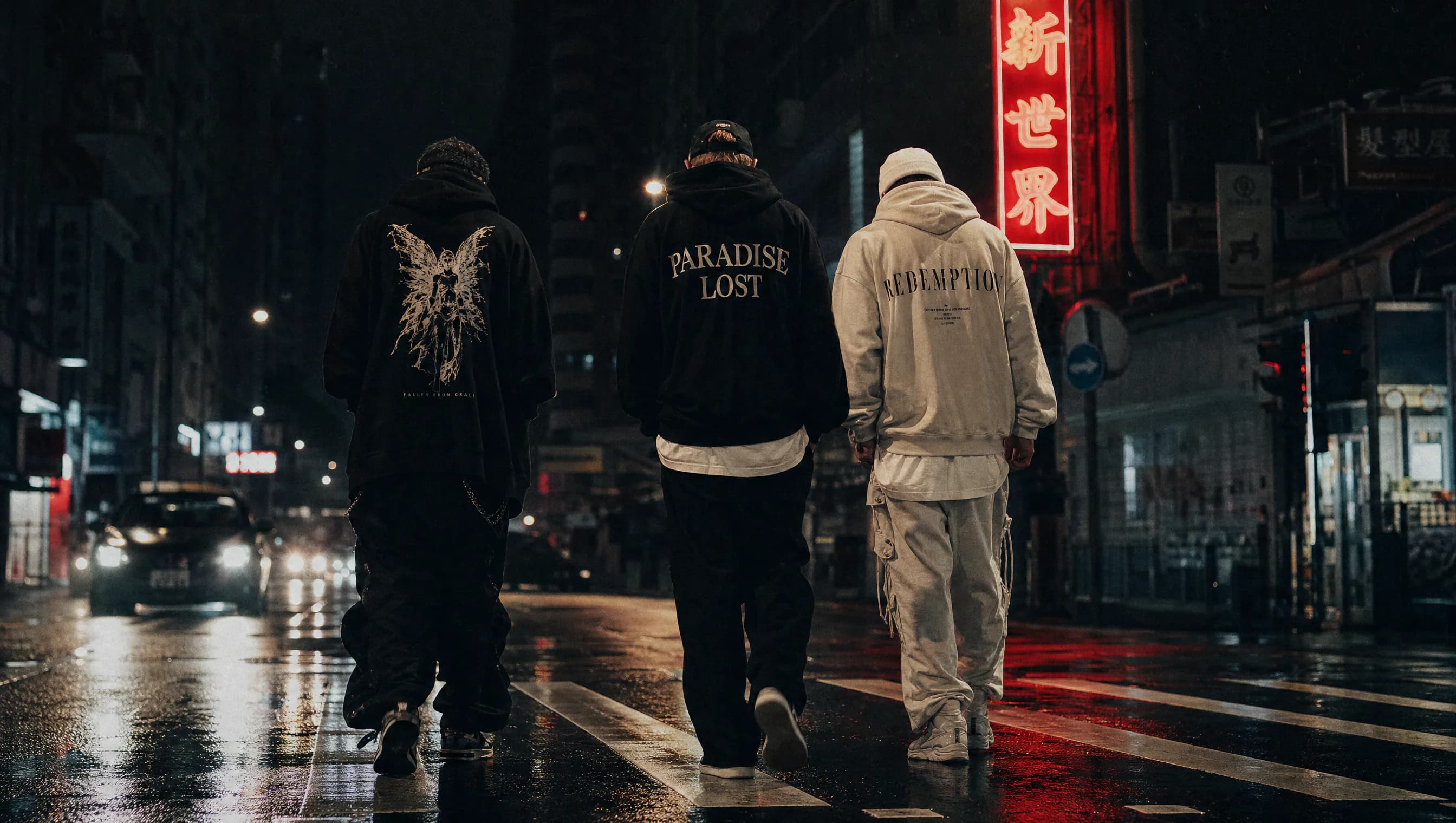Tres personas con streetwear oversize cruzando de noche una calle mojada por la lluvia